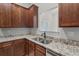 Close-up of the kitchen, boasting granite counters, stainless sink, and wood cabinets at 196 Al Jennah Blvd, Locust Grove, GA 30248