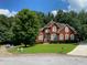 Inviting two-story brick home with mature trees, lush lawn, and a circular driveway at 3008 Sunrise Ct, Conyers, GA 30094