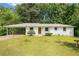 Charming white home featuring a covered carport and a well-maintained front yard, surrounded by lush greenery at 3055 Henderson Mill Rd, Atlanta, GA 30341