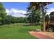 Landscaped backyard featuring a well-maintained lawn, mature trees, and stone walkway leading to a fence at 3905 Greenside Ct, Dacula, GA 30019