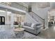 Open-concept living room with modern gray sofa, high ceilings, and staircase leading to the second floor at 3905 Greenside Ct, Dacula, GA 30019
