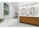 Bathroom featuring a modern tub, floating wood cabinets, and dual sinks at 4642 Orchid Dr, Pine Lake, GA 30072