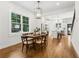 Open-concept dining area with hardwood floors, modern chandelier, and views to the kitchen and a large window at 4642 Orchid Dr, Pine Lake, GA 30072