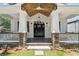 Inviting front porch with stone pillars, a dark front door with sidelights, and wood ceiling at 4642 Orchid Dr, Pine Lake, GA 30072