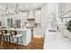 Modern white kitchen featuring a central island with bar stools, open shelving, and a stainless steel sink at 4642 Orchid Dr, Pine Lake, GA 30072