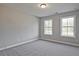 A well-lit bedroom with neutral walls, plush carpeting, and two large windows, offering a calming and inviting space at 687 Sunstone Ln, Lawrenceville, GA 30043
