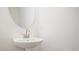 Bathroom featuring a sleek pedestal sink and a modern round mirror at 695 Sunstone Ln, Lawrenceville, GA 30043