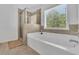 Bright bathroom features a tub with shower and a window view of the yard at 425 Eldridge Drive Dr, Suwanee, GA 30024