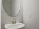 Powder room featuring a pedestal sink, oval mirror and neutral color palette at 689 Sunstone Ln, Lawrenceville, GA 30043