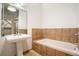 Bathroom features a pedestal sink, soaking tub with tiled surround, and large mirror at 1596 Cleveland Ave # 301, East Point, GA 30344