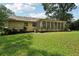 Backyard view featuring a lush lawn, mature trees, and the house which has a screened in porch and brick chimney at 2466 Country Club Dr, Conyers, GA 30013
