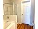 Well-lit bathroom featuring a glass shower, tub, and six-panel door at 3884 Grovemont Pl, Duluth, GA 30096