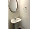 Pedestal sink and oval mirror in half bathroom with tile floors at 3884 Grovemont Pl, Duluth, GA 30096