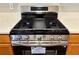 Close up of a stainless steel gas range and wood cabinets at 3884 Grovemont Pl, Duluth, GA 30096