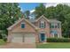 Charming brick home featuring a manicured lawn, two-car garage, and beautiful, bright blue front door and matching shutters at 5077 Wellisford Ct, Suwanee, GA 30024