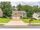 Lovely brick home with a two-car garage, lush green lawn, and mature trees in a quiet neighborhood at 5077 Wellisford Ct, Suwanee, GA 30024