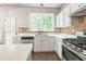 A kitchen featuring white cabinets, stainless steel appliances, and tile backsplash at 5077 Wellisford Ct, Suwanee, GA 30024