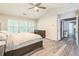 Bright main bedroom featuring wood-look flooring, large windows, and a ceiling fan at 5077 Wellisford Ct, Suwanee, GA 30024