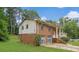 View of the side of a brick home featuring a covered front porch, and attached two-car garage at 115 Elizabeth Way, Ellenwood, GA 30294