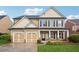 Charming two-story home with a two-car garage, a covered porch and manicured lawn and landscaping at 2040 Village Green Dr, Fairburn, GA 30213