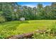 Expansive backyard showcasing a large grassy area, mature trees, and a convenient storage shed at 700 Walkingstick Dr, Douglasville, GA 30134
