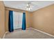 Neutral bedroom with plush carpeting, a ceiling fan, and a bright window with deep blue curtains at 700 Walkingstick Dr, Douglasville, GA 30134