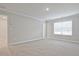 Bedroom with plush carpet and neutral walls featuring a large window and door to hallway at 905 Agate Ln, Lawrenceville, GA 30043