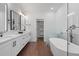 Bright bathroom featuring white cabinets, double vanity sinks, large mirrors, and a freestanding tub at 173 Brush Creek Ct, Stockbridge, GA 30281