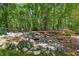 Scenic backyard showcasing a rock water feature amidst a lush, wooded environment at 3450 Saddleton Way, Douglasville, GA 30134