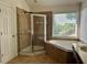 Bright bathroom featuring a glass shower, soaking tub, and a double vanity, offering a relaxing retreat at 1055 Havenstone Walk, Lawrenceville, GA 30045