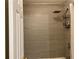 Bathroom featuring tiled shower with shower head and convenient storage shelves next to a white door at 1055 Havenstone Walk, Lawrenceville, GA 30045