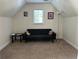Cozy bonus room with plush carpet, a comfortable futon, and natural light at 1055 Havenstone Walk, Lawrenceville, GA 30045