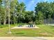 Community picnic area featuring green picnic tables on a concrete slab with mature trees and a tennis court nearby at 1055 Havenstone Walk, Lawrenceville, GA 30045