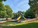 Community playground with green, yellow, and blue playset, surrounded by trees and greenery at 1055 Havenstone Walk, Lawrenceville, GA 30045