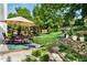 Beautiful backyard featuring a patio with dining set, mature trees, pergola, and stone retaining wall at 1490 Rivershyre Pkwy, Lawrenceville, GA 30043