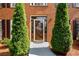 Close up of the front door with decorative glass and green foliage on either side at 1490 Rivershyre Pkwy, Lawrenceville, GA 30043