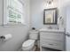 Cozy powder room with wood-framed mirror, toilet, and a single sink vanity with white cabinets at 1547 Grove Arbor Ter, Dacula, GA 30519