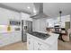 Modern kitchen features stainless appliances, white cabinets, island gas cooktop, and views into the living and dining area at 1547 Grove Arbor Ter, Dacula, GA 30519