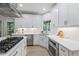 Spacious kitchen with modern stainless steel appliances, white cabinets, countertops, and a center island with gas cooktop at 1547 Grove Arbor Ter, Dacula, GA 30519