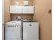Functional laundry room with white washer, dryer, and above-cabinet storage at 1547 Grove Arbor Ter, Dacula, GA 30519