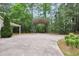Spacious driveway featuring a covered carport and ample parking space surrounded by lush greenery and mature trees at 280 W Knight W Rd, Mcdonough, GA 30252