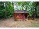 Rustic red outbuilding nestled in a wooded area, perfect for storage or a workshop at 280 W Knight W Rd, Mcdonough, GA 30252
