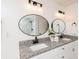 Bathroom offers dual sinks with granite countertops, modern lighting fixtures, and stylish oval mirrors at 932 Brian Ln, Forest Park, GA 30297