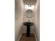 Stylish powder room featuring a black pedestal sink, round mirror, and modern lighting at 602 Birch River Ln, Lawrenceville, GA 30043