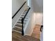 Elegant staircase featuring wood treads, white risers, and a black handrail at 602 Birch River Ln, Lawrenceville, GA 30043