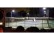 Lit tennis courts with fencing and a clubhouse in the background at night at 450 Hunt Creek Dr, Acworth, GA 30101