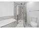 Clean bathroom with glass-door shower, soaking tub, toilet, and light gray tile at 57 Forsyth Nw St # 16G, Atlanta, GA 30303