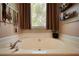 Bathroom with large soaking tub, window, and decorative accents at 1248 Rockview Ct, Loganville, GA 30052