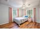 Cozy bedroom with hardwood floors, two windows dressed in pink curtains, and a ceiling fan at 2639 Hummingbird Nw Dr, Duluth, GA 30096