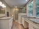 Bright bathroom featuring double granite vanities, a glass-enclosed shower, and a large window at 4512 Woodlawn Lake Dr, Marietta, GA 30068